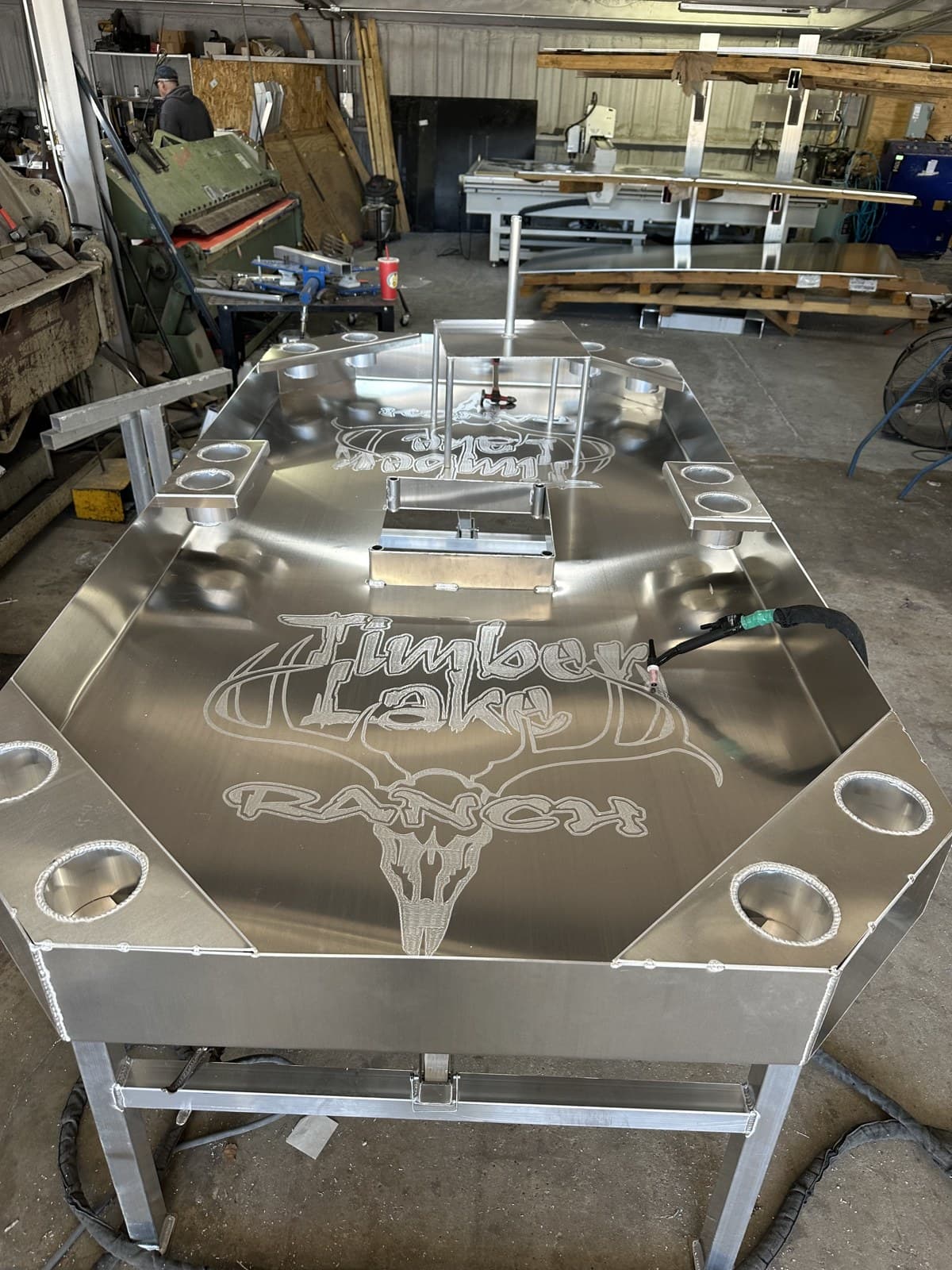 Octagonal aluminum crawfish table with twelve cup holders and a center strainer, ranch-logo engraving.
