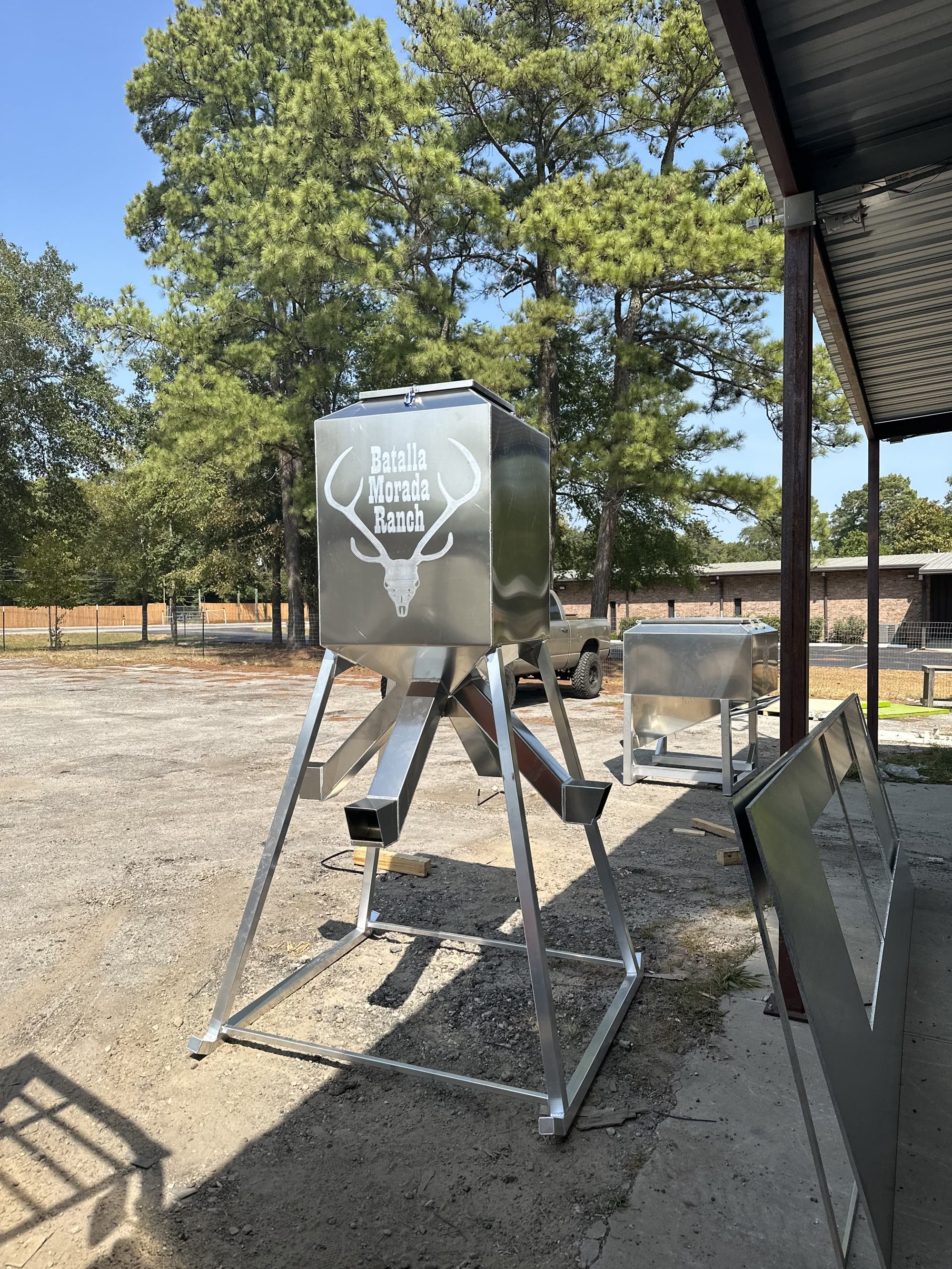 Aluminum Outfitters protein feeder on legs with four spouts, set up in a Texas pasture.