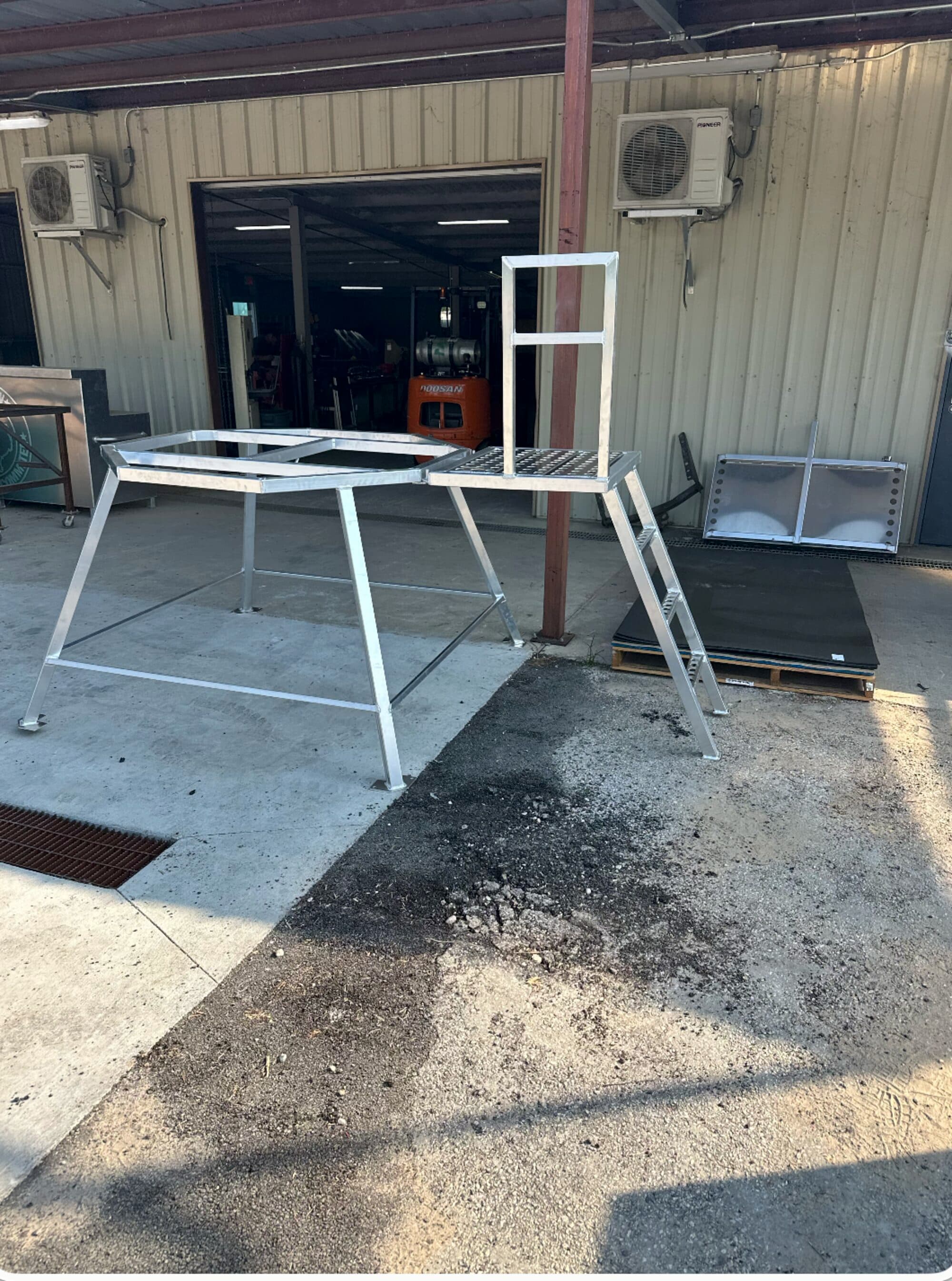 Uncle Dan's 4-foot aluminum platform with ladder and handrail, welded and ready outside the New Caney shop.