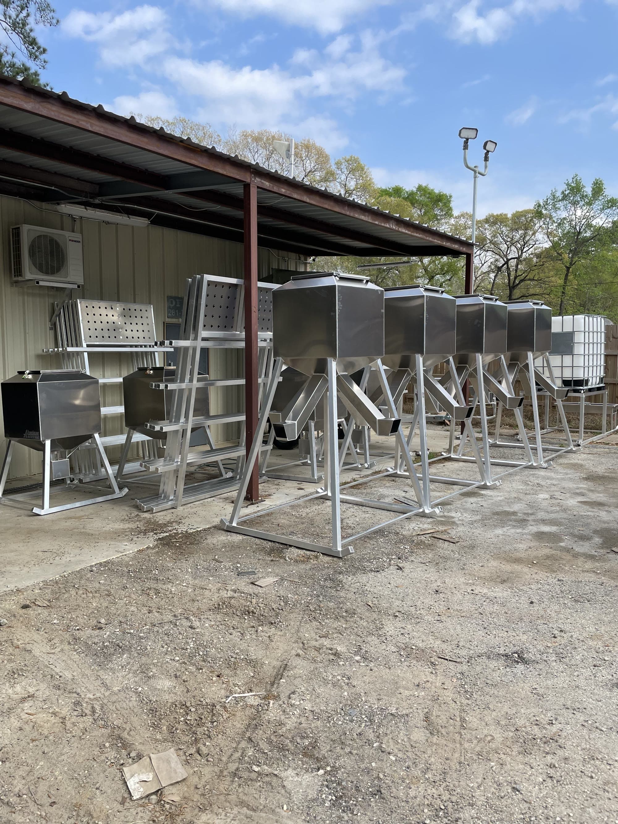A lineup of Aluminum Outfitters corn feeders in the yard, several sizes side by side.